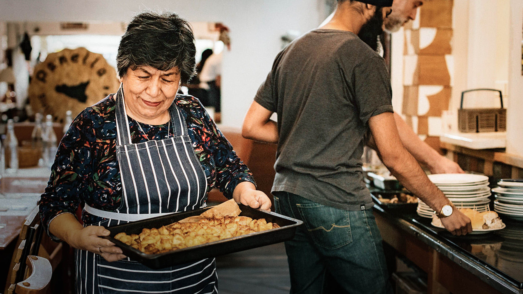 A woman serves a tray of food at the Goldfinger People’s Kitchen